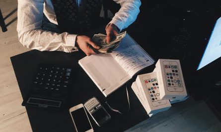 person counting money with smartphones in front on desk