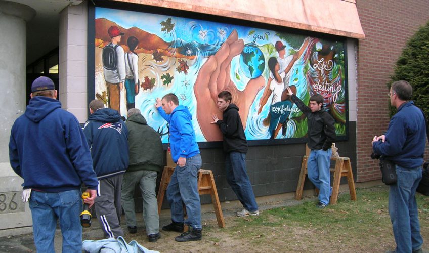 Students, community volunteers, building and grounds staff install exterior mural and pediment.