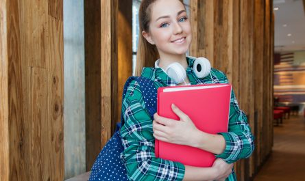 woman standing in hallway while holding book