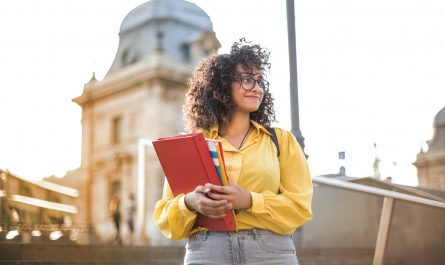 woman in yellow jacket holding red book