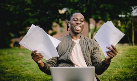 student with documents and laptop happy about getting into university