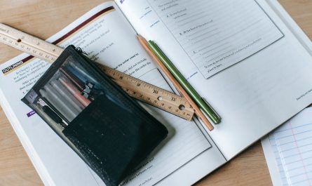 textbook with pens and ruler on table